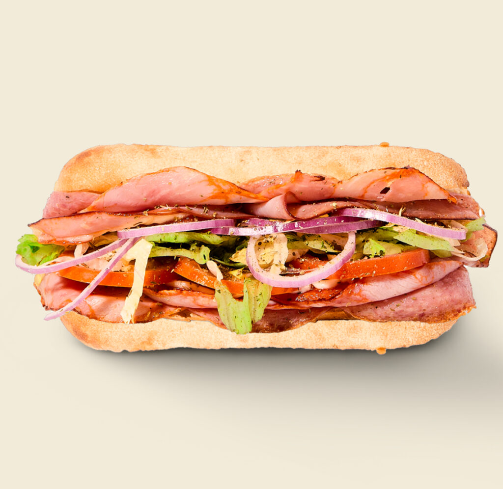 he Italian Sandwich, layered with premium salami, ham, spicy pepperoni, crisp lettuce, ripe tomatoes, red onions, tangy Italian dressing, and herbs, served on freshly baked artisan bread.