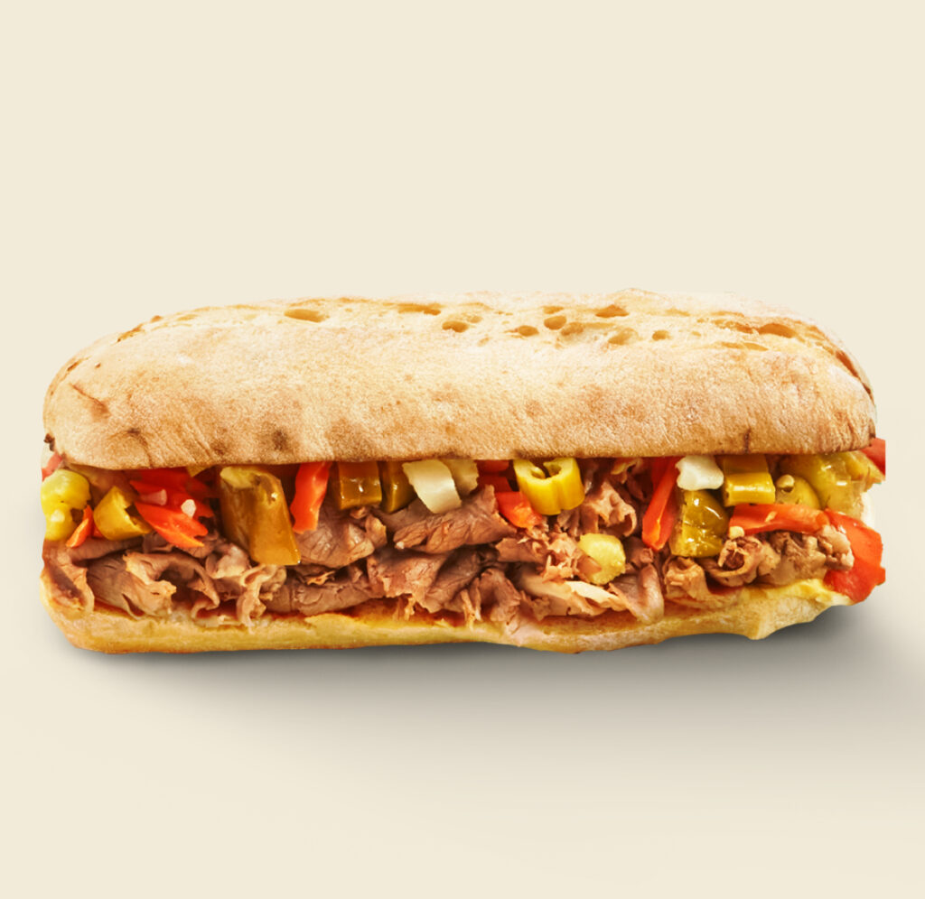 The Italian Beef Sandwich, featuring tender roast beef, spicy giardiniera, and savory au jus on freshly baked artisan bread.